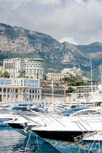 Boats in harbor by city against sky