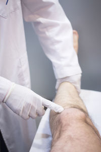 Midsection of doctor examining patient leg in hospital