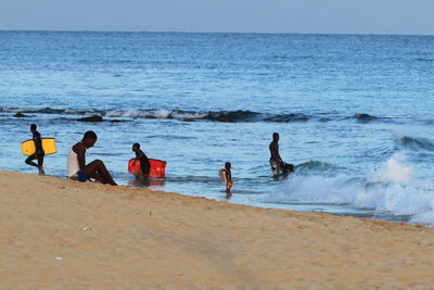 People on beach against clear sky