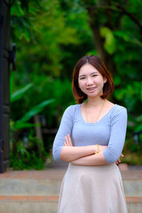 Portrait of smiling young woman standing against tree