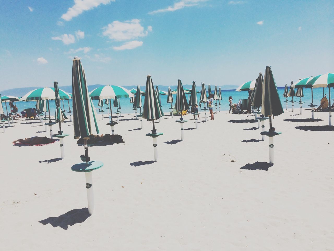 beach, sand, sky, blue, sea, beach umbrella, shore, sunlight, parasol, in a row, day, tranquility, arrangement, large group of objects, hanging, nature, vacations, absence, outdoors, shadow