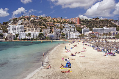 People on beach against buildings in city