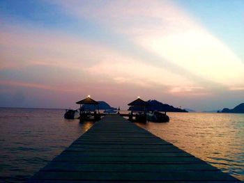 Pier over sea against sky during sunset