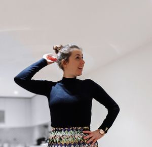 Young woman looking away while standing against wall