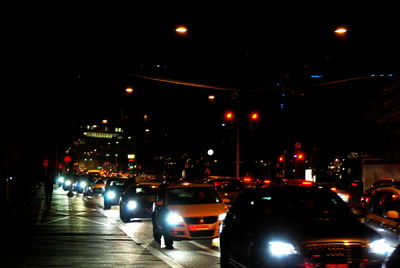 Cars on illuminated city against sky at night