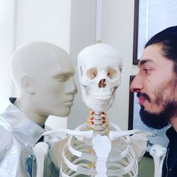 Close-up of man with mannequin and skeleton