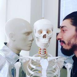 Close-up of man with mannequin and skeleton