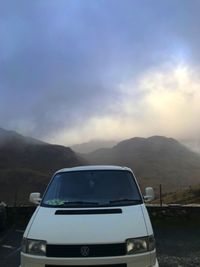 View of car on landscape against cloudy sky