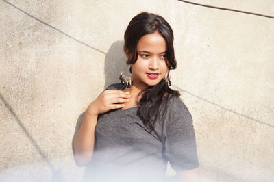 Thoughtful young woman standing against wall