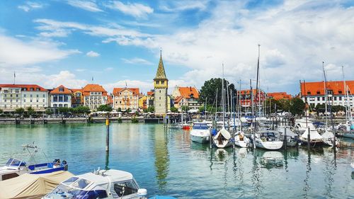 Sailboats moored in harbor against buildings in city