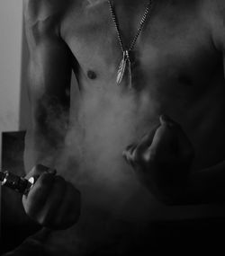 Midsection of shirtless man holding vape