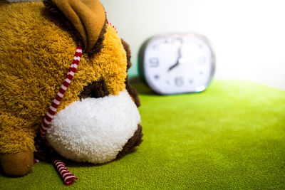 Close-up of teddy bear with clock on table