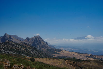 Scenic view of landscape and mountains against blue sky