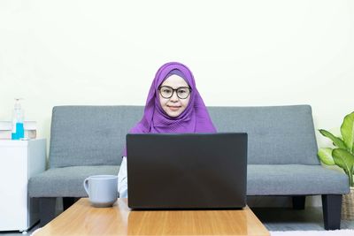 Portrait of man using laptop on table at home