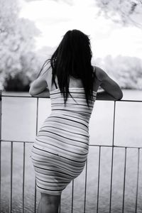 Rear view of woman standing against railing