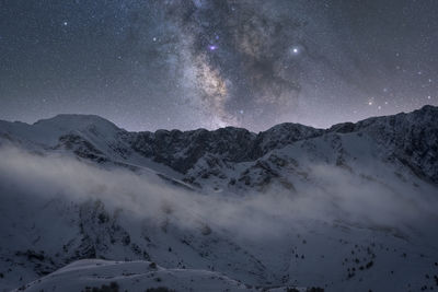 Scenic view of snowcapped mountains against sky at night