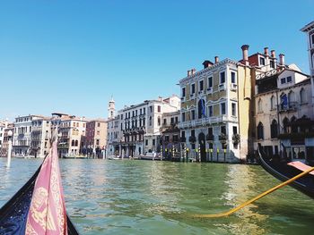 Boats in canal against clear blue sky