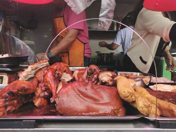 Midsection of street vendors cooking meat at market