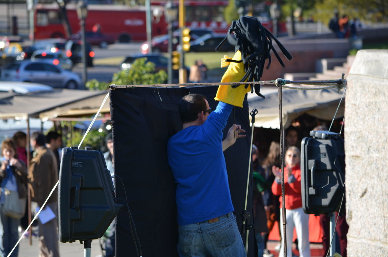 focus on foreground, men, street, lifestyles, occupation, incidental people, rear view, holding, city, leisure activity, person, outdoors, day, standing, market, working, building exterior, protection