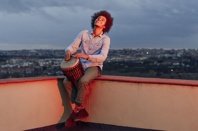 Full length of woman looking at cityscape against sky