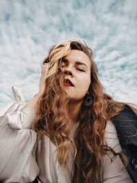 Beautiful young woman with closed eyes against sky