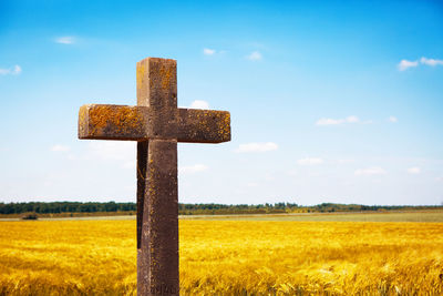 Cross on field against sky