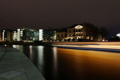 Reflection of buildings on river against sky at night