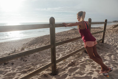 Woman exercising at beach against sky