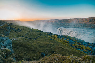 Scenic view of waterfall against sky during sunset