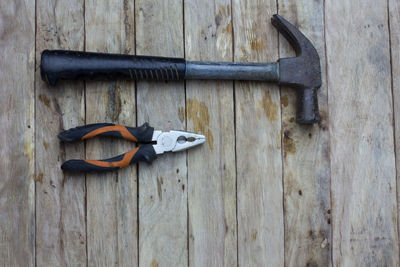 High angle view of hammer and plier on wooden table