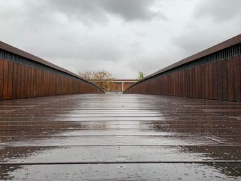 Surface level of wet bridge against sky during rainy season