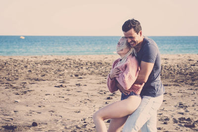 Happy couple embracing at beach during sunset