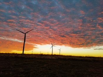 Low angle view of silhouette windmill on field against sky at sunset