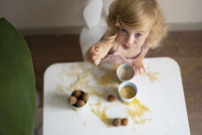 Toddler girl playing with grain, nuts, pasta and rice sitting at table.sensorial early development