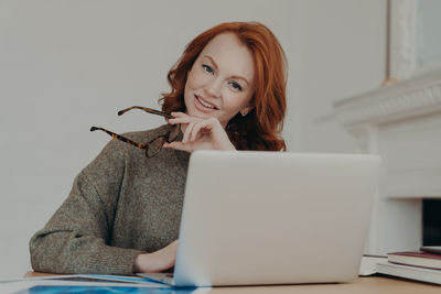 Portrait of smiling businessman using laptop in office