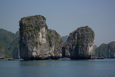 Rock formations by sea against clear sky