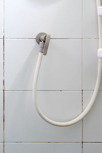 The white rubber strap with the brass faucet of the shower near the white wall in the shower box