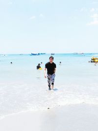 Portrait of man walking at beach against clear sky on sunny day