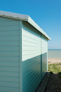 Building by sea against clear blue sky