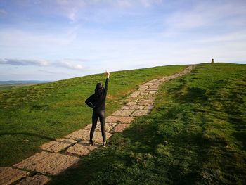 Full length of woman standing on footpath against sky