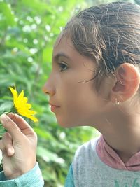 Close-up side view of girl holding yellow flower