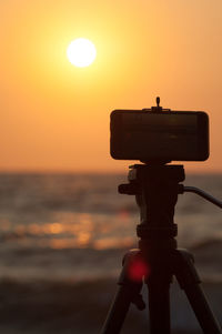 Silhouette cross on beach against sky during sunset