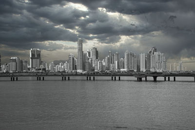 Sea by modern buildings against sky in city