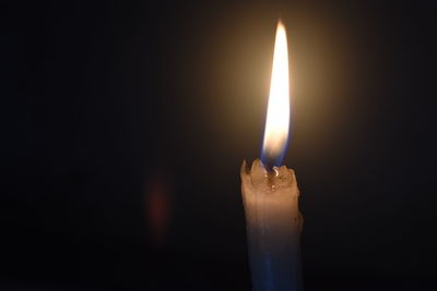 Close-up of lit candle against black background