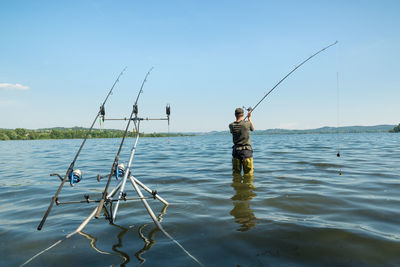 Man fishing in sea against sky