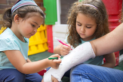 Little girls painting her mother's plaster arm