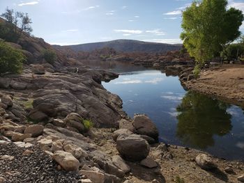 Scenic view of rocks by lake against sky