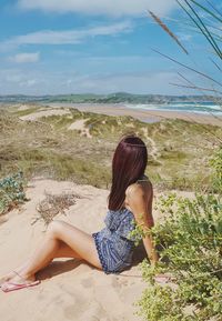 Full length of woman sitting on beach against sky