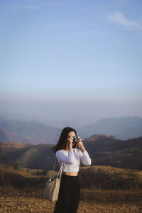 Young woman standing on mountain against sky