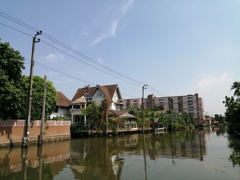 Houses by lake and buildings against sky